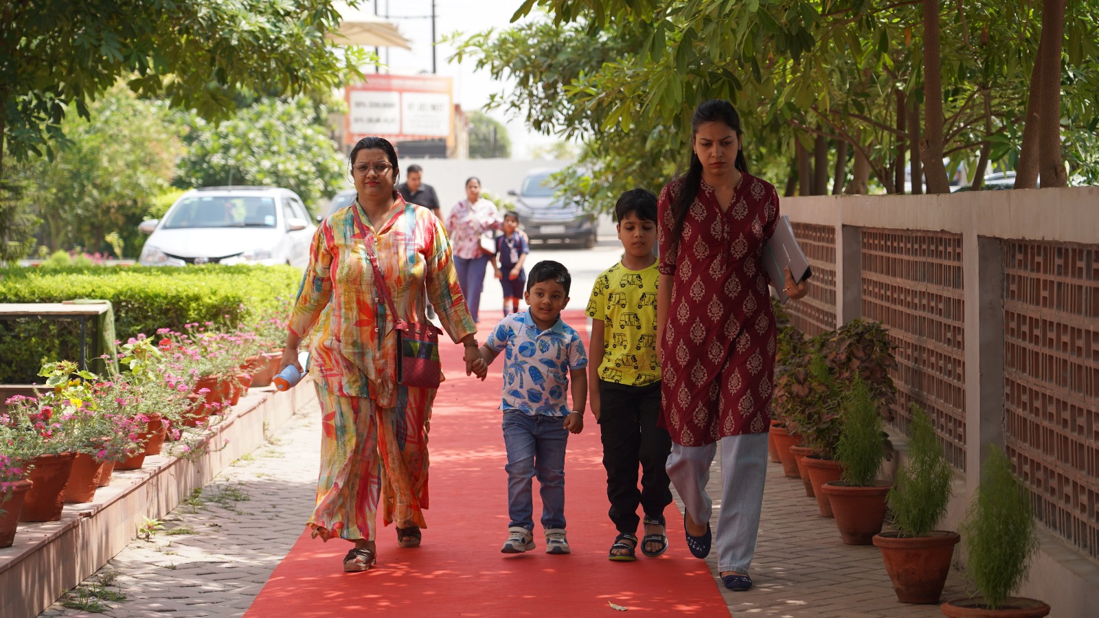 Parents walking their children up the red carpet to the Khaitan World School entrance